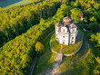 © pyty - Aerial view of the Church of Saint John the Baptist and Our Lady of Mount Carmel surrounded by lush greenery at Makova Hora, Czechia, on a bright spring day.
