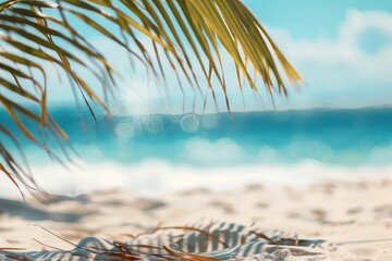 The summer concept shows a beautiful sandy beach with tropical palm leaves on a blurry ocean background