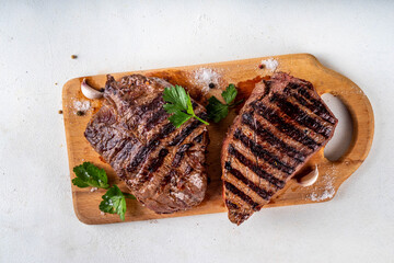 Wall Mural - Grilled beef steak on wooden cutting board with ketchup sauce and condiments, top view copy space