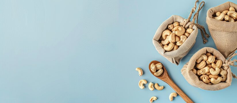 Cashews as a snack Snacks placed in sacks and placed on a wooden spoon area, pastel background. with copy space image. Place for adding text or design