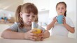 © maxximmm - children drink juice. little girl in the kitchen drinking yellow juice from a glass cup. happy family kid dream concept. children drink juice in the kitchen. healthy eating concept fun