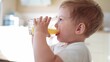 © maxximmm - children drink juice. little boy in the kitchen drinking yellow juice from a glass cup. happy family kid dream concept. children drink juice in the kitchen. healthy eating fun concept