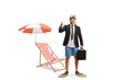 © Ljupco Smokovski - Businessman with snorkelling fins and mask holding a briefcase and showing thumbs up next to a beach chair