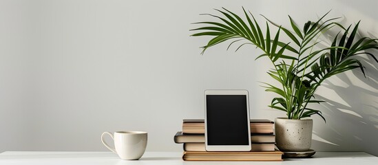 Poster - Stylish workspace with digital tablet, books, coffee cup and houseplant on white desk. with copy space image. Place for adding text or design