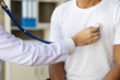 © Wasan - Doctor using stethoscope examining male patient for diagnosis in hospital examination room.