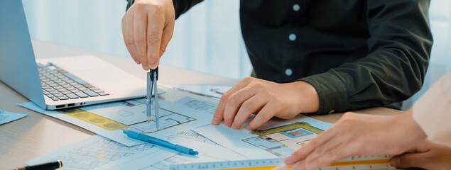Wall Mural - A cropped image of professional engineer using divider to measure blueprint at meeting table with blueprint, laptop and architectural equipment scatter around. Closeup. Delineation.