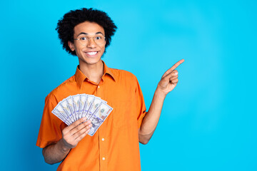 Wall Mural - Photo of funky cool guy dressed orange shirt eyeglasses rising money fan pointing emtpy space isolated blue color background