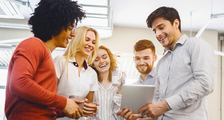 Aufkleber - A multiethnic group of individuals are gathered together, standing around a tablet device, engaged and focused on the content displayed on the screen, discussing or collaborating on a project.