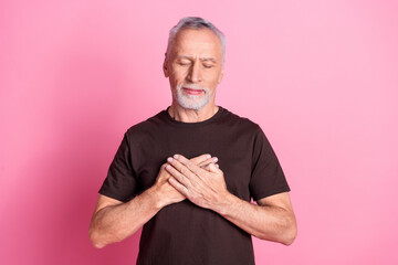 Poster - Portrait of kind appreciative man with white gray beard dressed brown t-shirt holding hands on chest isolated on pink color background