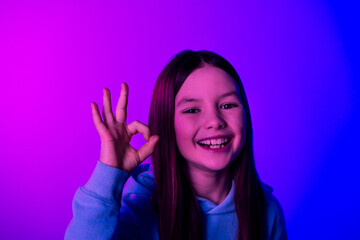 Poster - Photo of cheerful pretty little lady dressed hoodie showing okey gesture empty space isolated neon purple color background