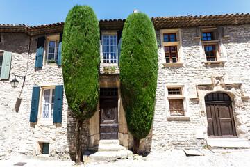 Facade of old Medieval houses with cypress trees in Vaison la Romaine, Provence, France, Europe