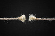 © fotoyou - Frayed Rope About to Break Against Textured Black Paper Background with Copy Space