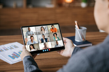 Aufkleber - A person is sitting at a desk and looking at a tablet computer. The tablet is displaying a video conference with eight people. The people are all smiling and looking at the camera.