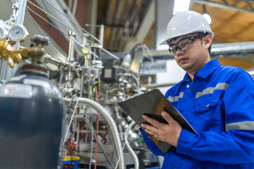 Asian engineer working at Operating hall,Thailand people wear helmet  work,He worked with diligence and patience,she checked the valve regulator at the hydrogen tank.