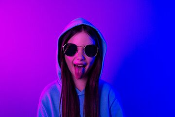 Sticker - Photo of cheerful funny little lady dressed hoodie dark glasses stick out empty space isolated neon purple color background