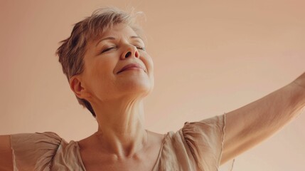 Wall Mural - Woman with closed eyes smiling and arms raised in a joyful or celebratory gesture against a soft-focus pink background.