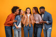 © Prostock-studio - Multiracial friends engaged in a playful and secretive moment, with four of them leaning in to whisper to the woman in the center