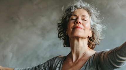 Wall Mural - Woman with closed eyes smiling and arms outstretched in a pose of joy or surrender against a soft textured background.