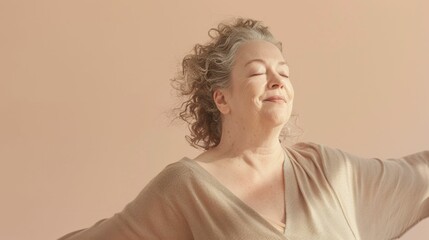 Wall Mural - Elderly woman with closed eyes smiling in a light-colored draped garment against a soft warm background.