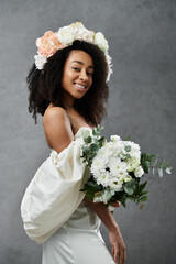 Wall Mural - A beautiful African American bride in a white wedding dress with a flower crown in her hair, smiling against a gray background.