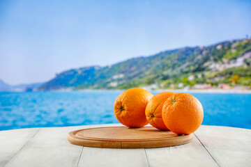 Sticker - Fresh citrus fruit on wooden table top with beautiful summer landscape of calm sea and blue sky.