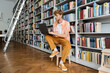 © LIGHTFIELD STUDIOS - A young man immerses himself in study, typing on a laptop in a library chair.