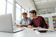 © LIGHTFIELD STUDIOS - Two young men focus on laptop screen, engrossed in study session at table.