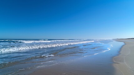 Wall Mural - A serene, empty beach with gentle waves and a clear, blue sky