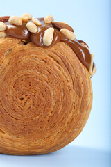 Wall Mural - One supreme croissant with chocolate paste and nuts on light blue background, closeup. Tasty puff pastry