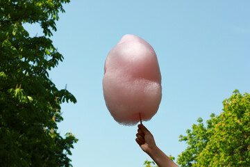 Wall Mural - Woman holding sweet cotton candy against blue sky, closeup