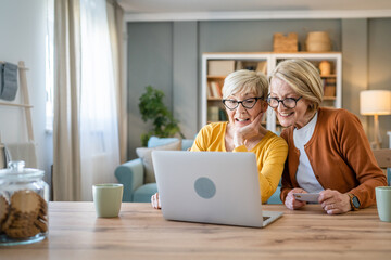 Senior women two females hold credit card online shopping at home