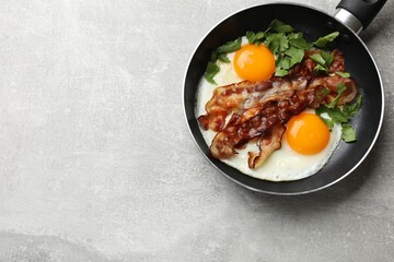 Wall Mural - Tasty bacon, eggs and parsley in frying pan on gray textured table, top view. Space for text