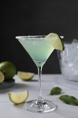 Wall Mural - Delicious Margarita cocktail in glass and limes on white wooden table