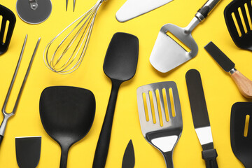 Wall Mural - Different spatulas and other kitchen utensils on yellow background, flat lay
