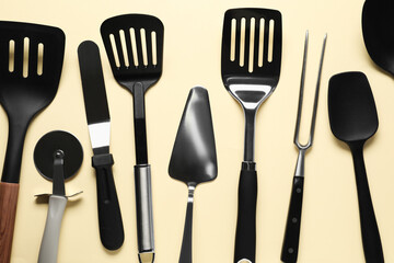 Wall Mural - Different spatulas and other kitchen utensils on beige background, flat lay