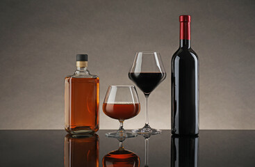 Wall Mural - Bottles and glasses with different alcoholic drinks on table against gray background