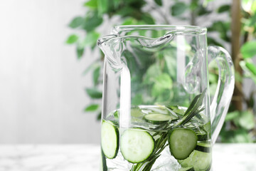 Sticker - Refreshing cucumber water with rosemary in jug on blurred background, closeup. Space for text