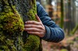 © Maxim Borbut - An avid nature lover hugs a trunk tree in tropical woods with green musk. Green natural background. A concept of people to protect nature from pollution, deforestation, and climate change.