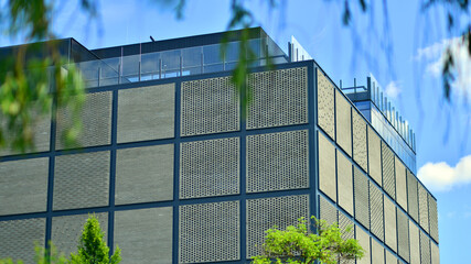 Wall Mural - Exterior of a modern industrial building with green environment. Corporate building reduce CO2. Eco building.