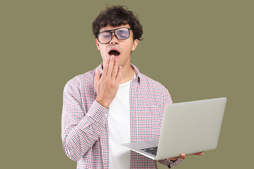 sleepy male programmer with laptop on green background
