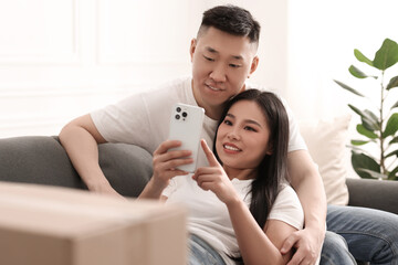 Wall Mural - Happy couple with smartphone in their new apartment