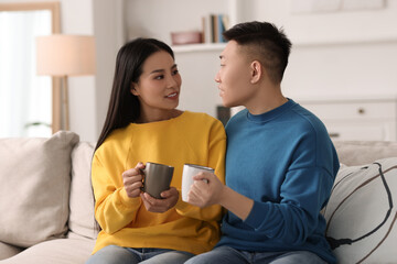 Canvas Print - Happy couple with cups of drink on sofa at home