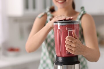 Sticker - Woman making delicious smoothie with blender in kitchen, closeup