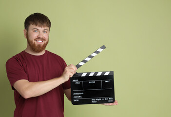 Poster - Making movie. Smiling man with clapperboard on green background. Space for text