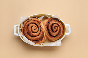 Wall Mural - Baking dish of tasty cinnamon rolls on beige background