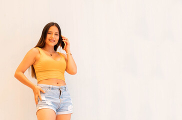  Primer plano de una mujer joven en un traje de verano en un top amarillo con celular.Mujer feliz posando aislada sobre fondo de pared gris hablando por teléfono móvil feliz, sonrisa,