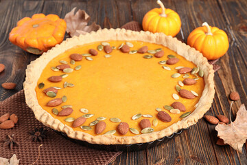 Wall Mural - Delicious pumpkin tart with almond and seeds on wooden background