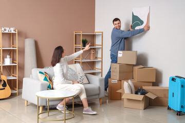 Wall Mural - Happy young couple with painting in room on moving day