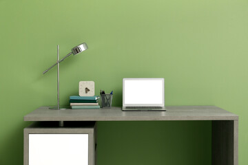 Wall Mural - Stylish workplace with stationery and laptop near green wall