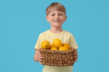 Poster - Cute little boy with basket of lemons on blue background